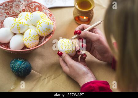 Lithuanian girl painting traditional Easter eggs with hot beeswax using a needle Stock Photo