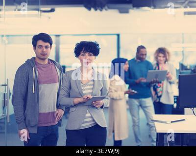 Mixed race male and female standing near colleagues in office Stock Photo