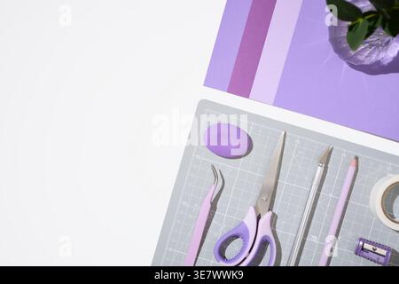 Purple craft supplies and paper sheets on white background with copy space. Stock Photo