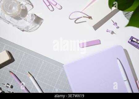 Pastel workspace flat lay with notebook, pen, tape, pins and stationery on white desk. Setup for planning, office work and school organization. Copysp Stock Photo