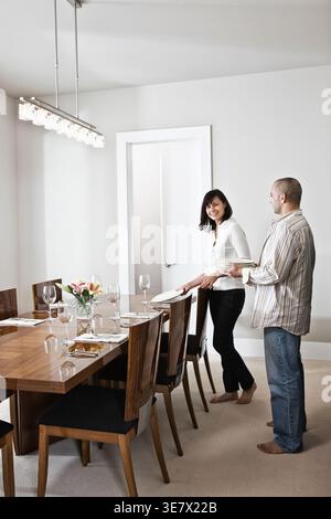 Black, Middle Eastern man helping wife in setting dining table at home Stock Photo