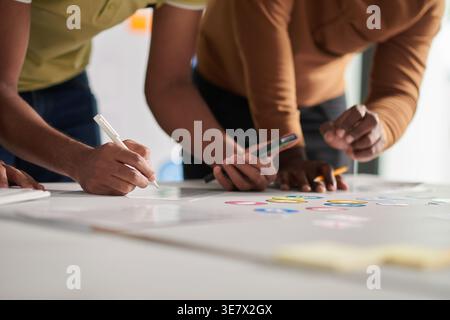 Indian male UI and designers standing and leaning forward on table working on interface and icon for new mobile app in office Stock Photo