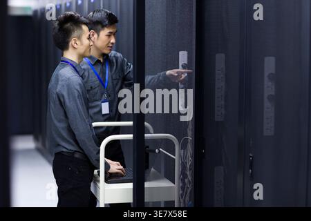 Chinese male technicians doing maintenance using laptop in computer room Stock Photo
