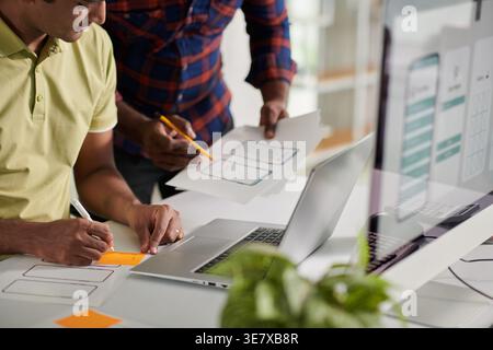 Asian male designers holding pen and paper working together in office during daytime Stock Photo