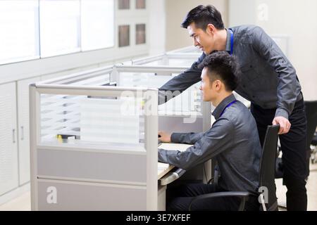 Chinese male computer programmers working together on laptop in office Stock Photo