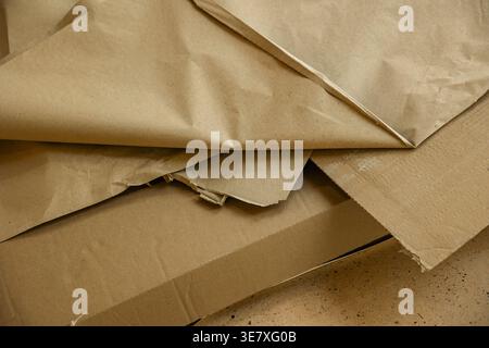 Crumpled brown packing paper on floor in indoor space, used material texture. Concept: packaging waste Stock Photo