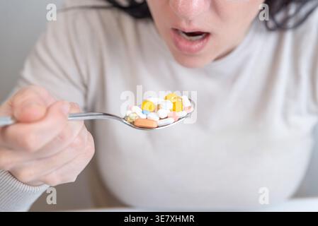 Close up of woman about to take spoon full of pills, extreme medication concept Stock Photo