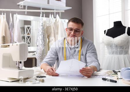 Dressmaker working with sewing pattern at white table in atelier Stock Photo