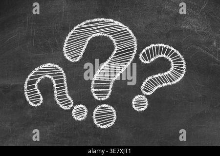 Three question marks drawn on black chalkboard Stock Photo