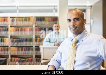 Middle Eastern male dentist with white male sitting behind in office Stock Photo
