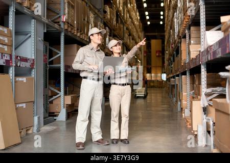 Chinese male and female workers standing and doing inventory together in distribution warehouse Stock Photo