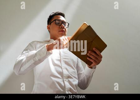 Asian male graphic designer using digital tablet while standing in office Stock Photo