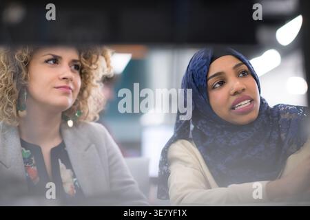 Black woman with hijab having meeting with caucasian female coworker sitting in office Stock Photo