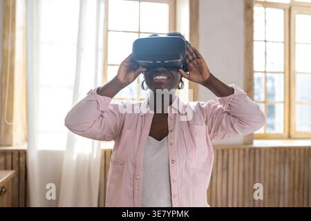Black woman with afro experiencing VR glasses standing in kitchen at home Stock Photo