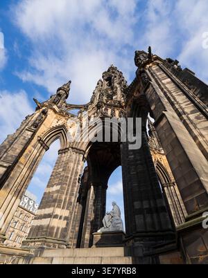 The Scott Monument, a Victorian Gothic monument to Sir Walter Scott, stands tall against a bright blue sky with fluffy clouds Stock Photo