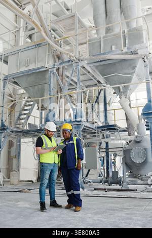 Mixed-race female and caucasian male engineers using tablet together standing in factory Stock Photo