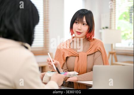 Asian female graphic designers working on their new design project while sitting at table in office Stock Photo