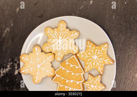 White round plate holding five decorated sugar cookies sitting on dark stone countertop Stock Photo