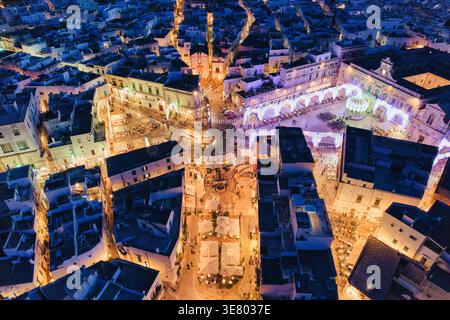 Aerial night view of the 'White City' Ostuni in Puglia, Italy; crowded town square decorated with traditional Luminarie lights in summer Stock Photo