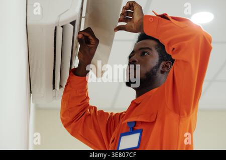 Black male technician examining air conditioning system in costumer's home Stock Photo