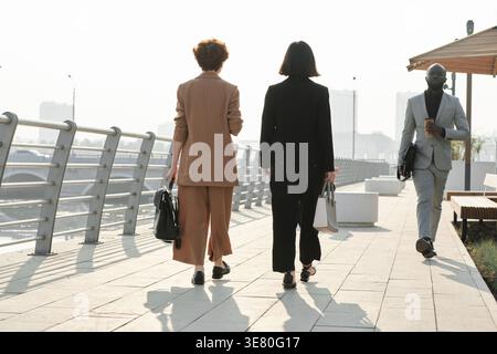 Group of office workers walking along the river bank on sunny day Stock Photo