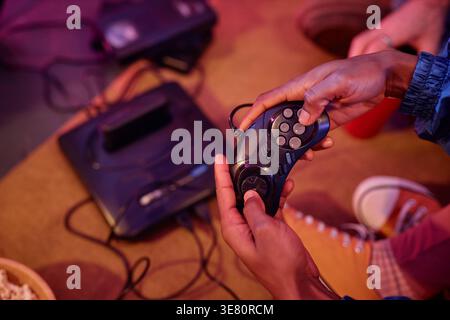 Cropped image of African American woman hands holding joystick playing video game during house party Stock Photo