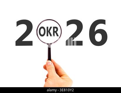2026 OKR objectives and key results symbol. Concept words 2026 OKR in magnifying glass. Beautiful white background. Businessman's hand. Business 2026 Stock Photo