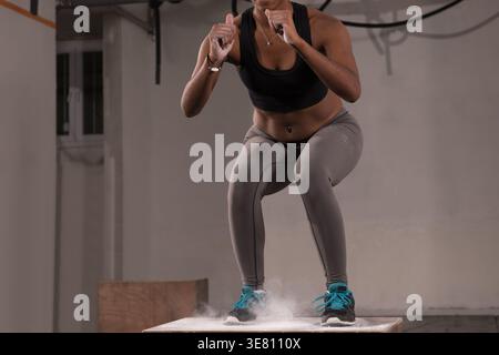 Black woman wearing activewear exercising doing squats on box in gym Stock Photo