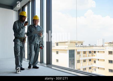 Black male engineer and Asian male contractor managing work at construction site Stock Photo