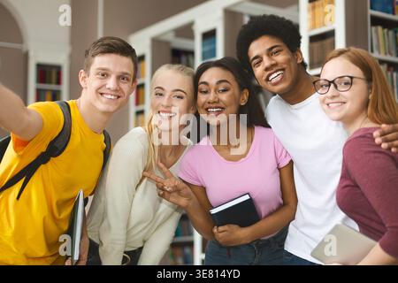 Diverse group of college students taking selfie in library Stock Photo