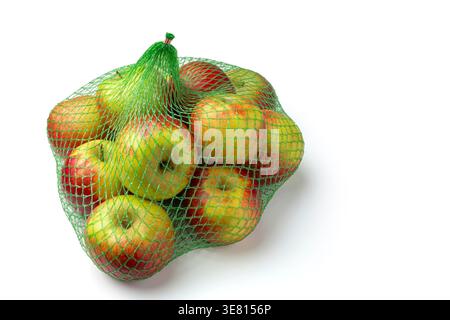Healthy harvest of sweet apples in a reusable mesh bag over a clean white surface Stock Photo