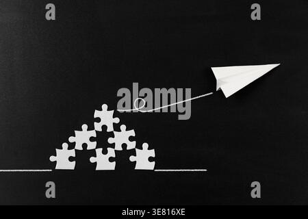 Creative concept of a paper plane launching from puzzle pieces on a dark background, symbolizing problem solving, progress, innovation, and turning ideas into action. Stock Photo