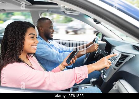 Smiling Black couple using smartphone navigating way while riding car together in city Stock Photo
