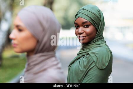 Black and Middle Eastern women wearing hijabs standing in city park during daytime Stock Photo