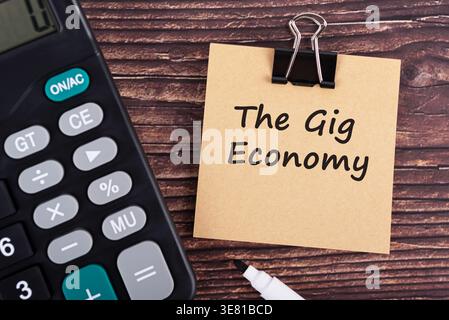 Calculator and The gig economy text on brown memo pad Stock Photo
