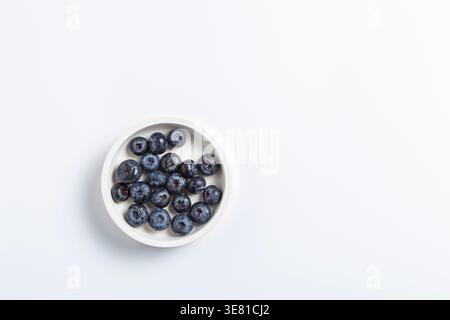A top-down view of fresh, ripe blueberries gathered in a small white ceramic bowl. Stock Photo