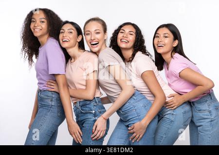 Diverse group of women embracing having fun while standing against white background in studio Stock Photo