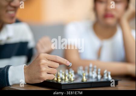 Cropped image of Asian man taking chess piece while paying with friend in living room at home Stock Photo