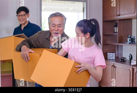 Senior Asian father with son and daughter carrying boxes moving into their new home Stock Photo