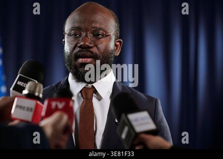 Black male politician wearing eyeglasses giving interview to journalists holding microphones during press conference Stock Photo