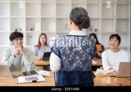 Asian female teacher giving lecture to her students in classroom Stock Photo