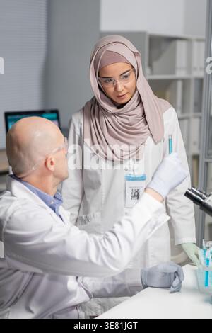 Serious Asian female scientist looking at flask of liquid in the laboratory clinic Stock Photo
