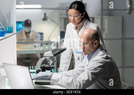 Serious Mixed race female scientist standing and looking at the laptop in the laboratory clinic Stock Photo