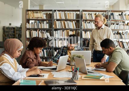 Group of students studying together while sitting at table in library Stock Photo