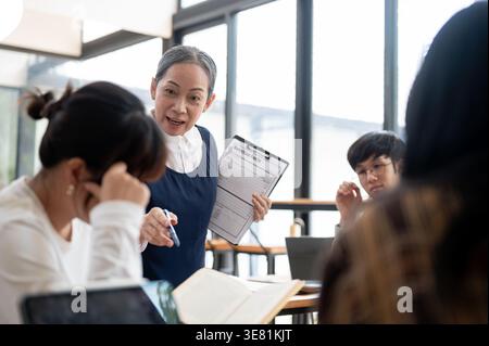 Asian female teacher giving lecture to her students in classroom Stock Photo