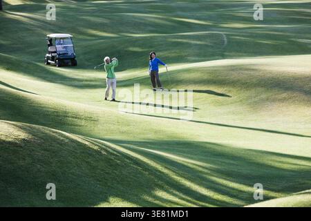 Asian couple playing golf standing near golf cart in golf course Stock Photo