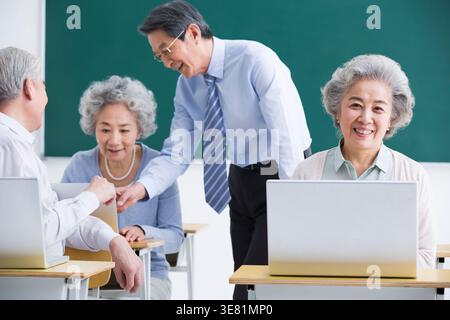 Senior Chinese men and women having computer classes in school Stock Photo
