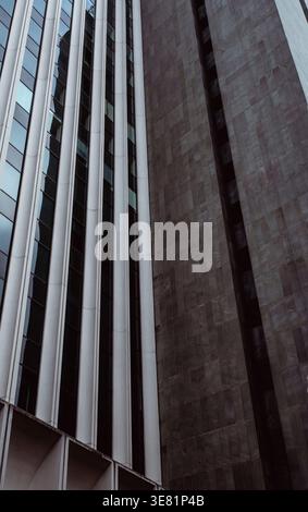 Modern building facade with vertical panels. Metallic surfaces create geometric patterns. Monochrome tones enhance a minimalist aesthetic. Stock Photo