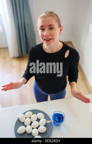 Coloring white eggs with blue dye, festive home ritual and creative spring moment. Stock Photo