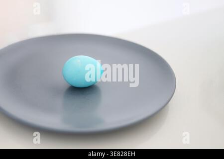 Single blue Easter egg on a plate, minimal composition and soft light, symbol of holiday simplicity and clean lifestyle. Stock Photo